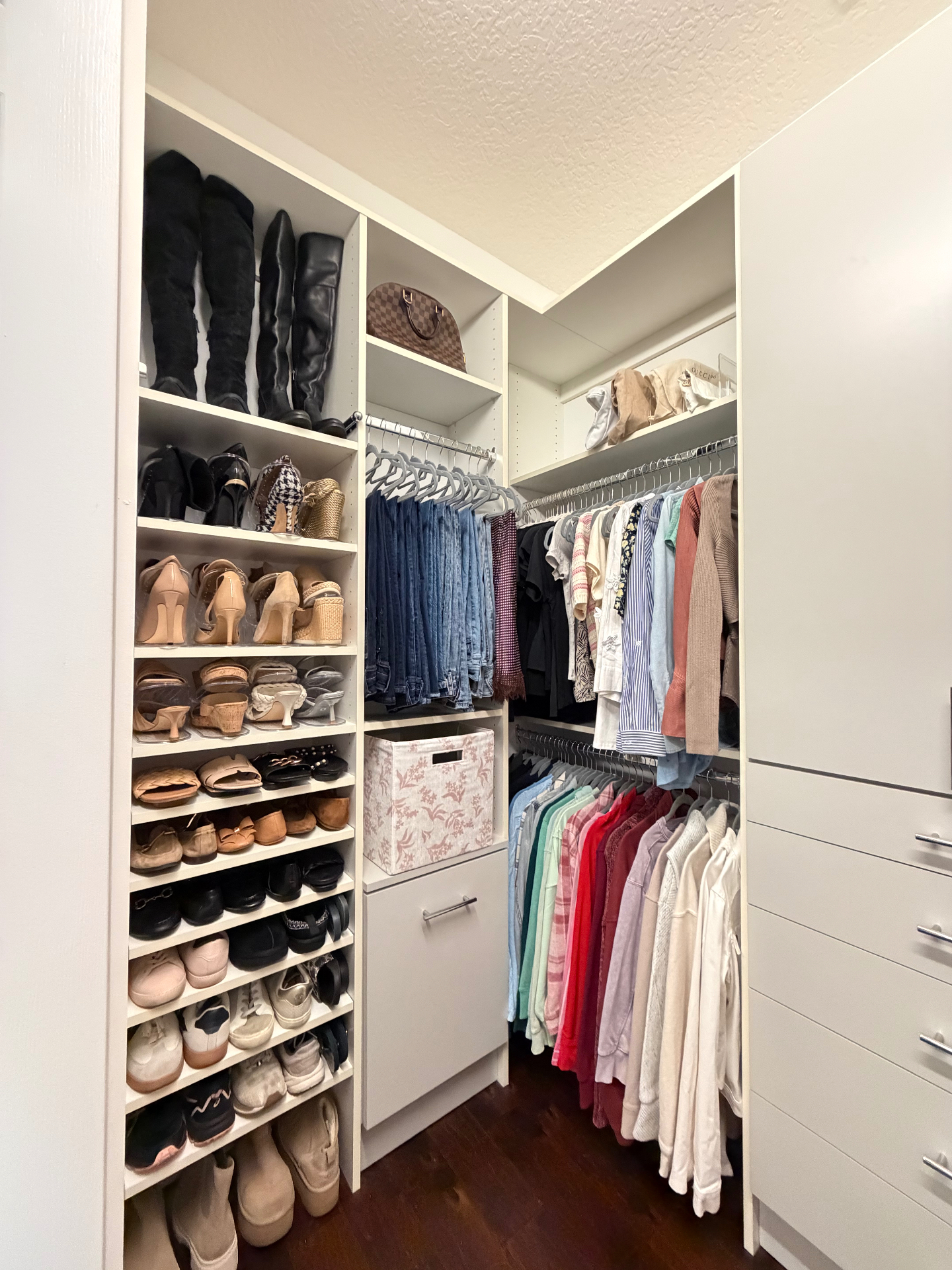 A beautifully organized walk-in closet with color-coordinated clothing, shoe shelves, and handbag storage